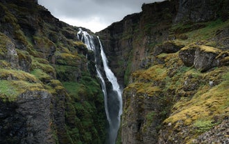 Glymur Waterfall plunges into a mossy canyon surrounded by rugged cliffs.