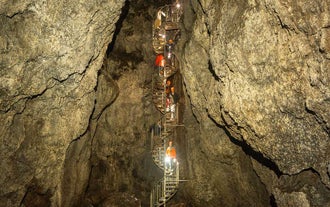 Tour group descends a spiral staircase deep inside Vatnshellir Cave’s volcanic chamber.