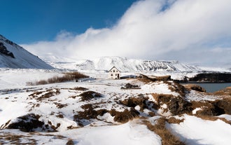 Snow-covered lava fields and coastline with distant mountains on the Snaefellsnes Peninsula.