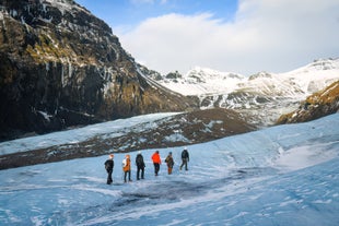 A group of travelers begins a glacier hike on Solheimajokull as the surrounding mountains offer breathtaking views.