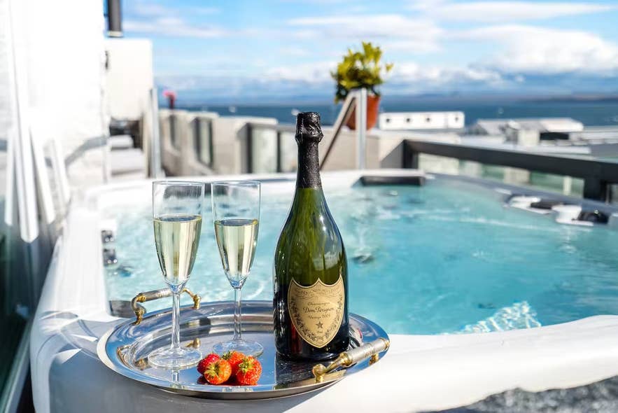 Eine Flasche und zwei Gläser Champagner auf einem Tablett neben dem Whirlpool der Diamond Suites in Keflavik.