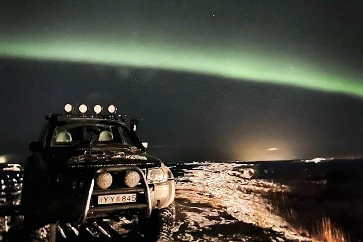 A super jeep under the northern lights at night in Iceland.