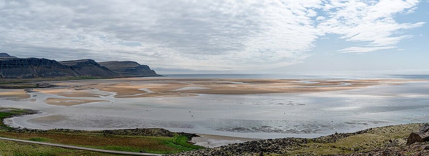 Panoramic view of Raudisandur Beach with tidal flats and cliffs in Iceland.