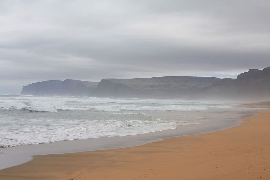 Misty waves on golden sand at Raudisandur Beach, Iceland