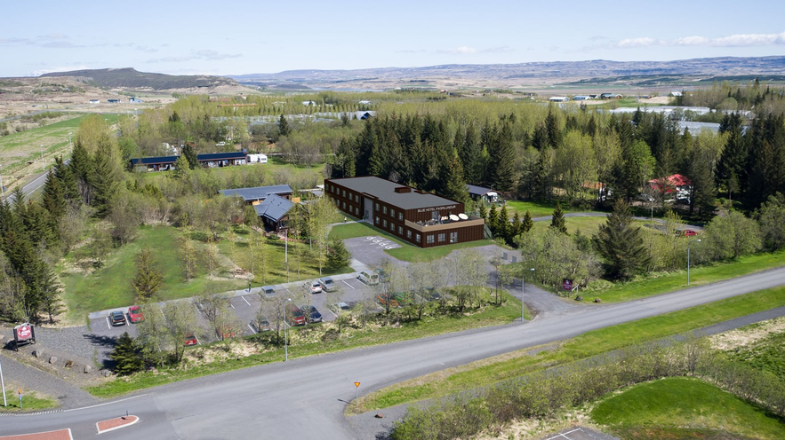 Aerial view of Blue Hotel Fagrilundur, nestled in greenery near Iceland’s Golden Circle with parking and forest surroundings.