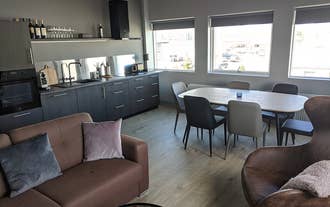 Open-plan kitchen and living area with dining table, sofa, and large windows in apartment in Akureyri.