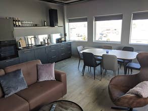 Cuisine ouverte et séjour avec table à manger, canapé et grandes fenêtres dans un appartement à Akureyri.