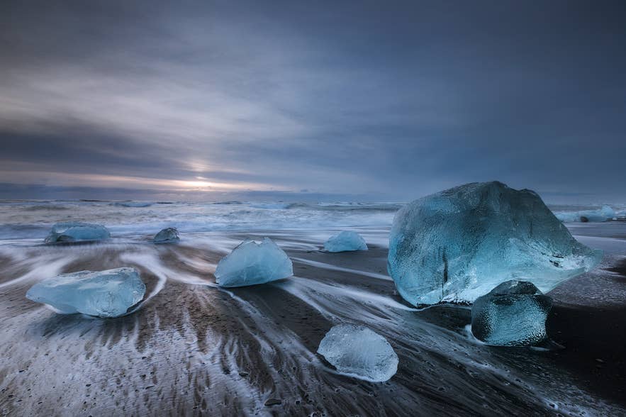 Des morceaux de glace glaciaire sont éparpillés sur la Plage de diamants en Islande, brillant comme des pierres précieuses sur le rivage de sable noir.