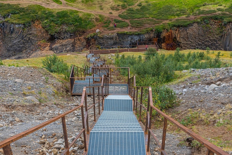 Metal stairs leading to the main viewing platform at Studlagil Canyon in East Iceland, offering safe access to the basalt column gorge.