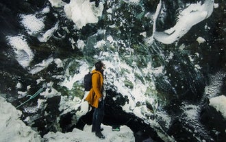 A traveler looks up at the nearly black ice of a natural ice cave on Langjokull glacier.