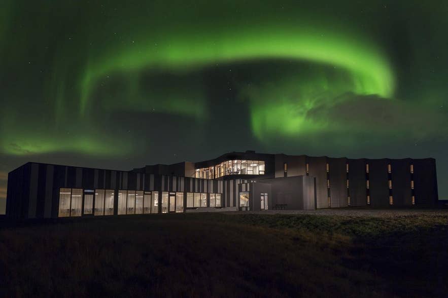 Landhotel con l'aurora boreale sopra la struttura. 