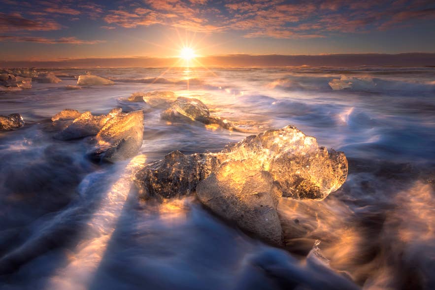 Waves wash over glacial ice at Diamond Beach on Iceland's South Coast at sunrise, on the coast where wind matters most to visitors.