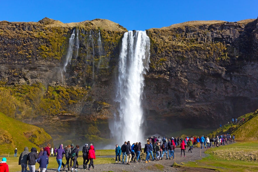 Crowds gather at Seljalandsfoss Waterfall, a popular natural attraction in Iceland in July.