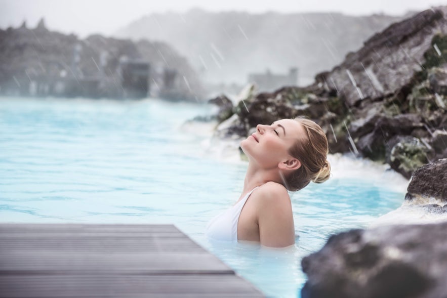A woman with her eyes closed is enjoying the calm, warm waters of the Blue Lagoon.