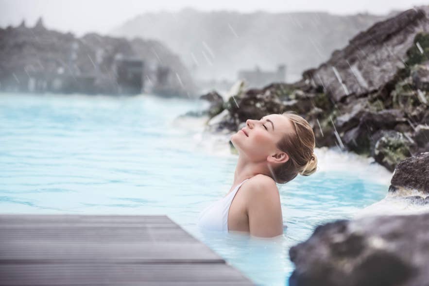 A bather with eyes closed relaxing in the calm, warm water of the Blue Lagoon