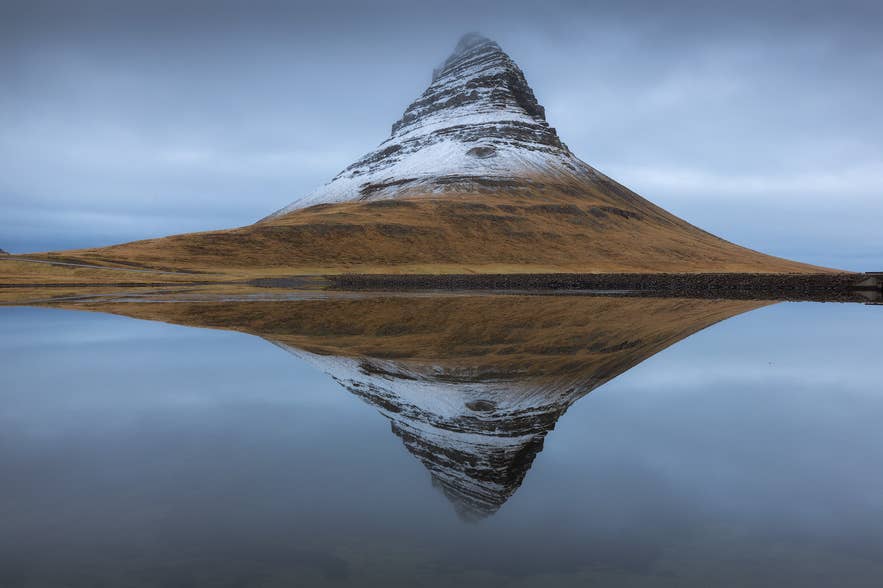 Kirkjufell met een laagje sneeuw in de vroege winter, weerspiegeld in het water.