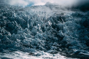 Jagged black and white glacier ice in South Iceland with misty air above.