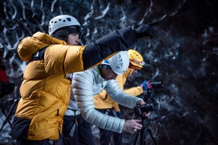 Three people adjust their cameras on a photography tour in South Iceland.