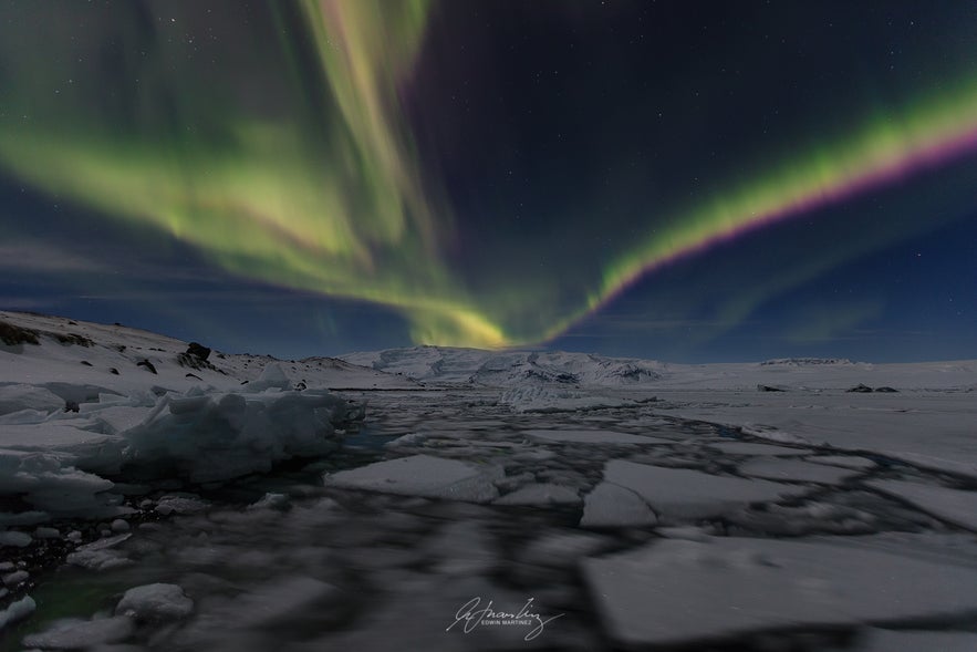 Northern lights over icy landscape in Iceland, one of the top reasons to visit Iceland for nature and adventure lovers.