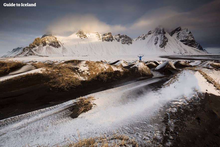 Snow-covered black sand dunes at Vestrahorn mountain in southeast Iceland with dramatic winter skies