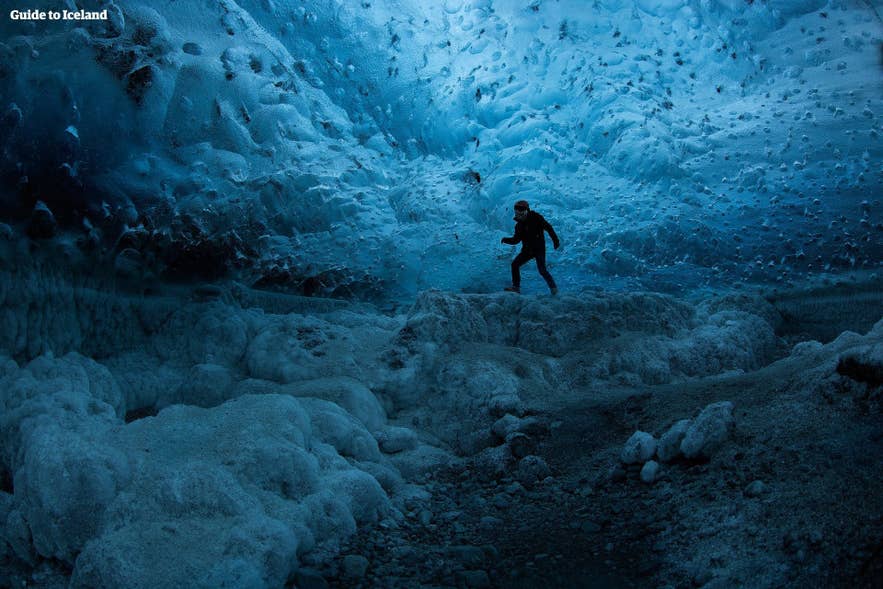 冬のヴァトナヨークトル氷河の下、青い氷の洞窟を探検する旅行者