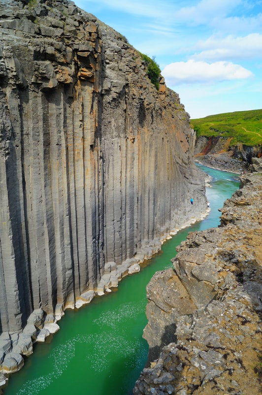 Eine Draufsicht zeigt die imposante Größe der vertikalen Basaltsäulen in der Studlagil-Schlucht und das türkisfarbene Wasser darunter.