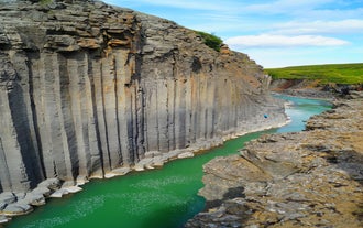 Eine Draufsicht zeigt die imposante Größe der vertikalen Basaltsäulen in der Studlagil-Schlucht und das türkisfarbene Wasser darunter.
