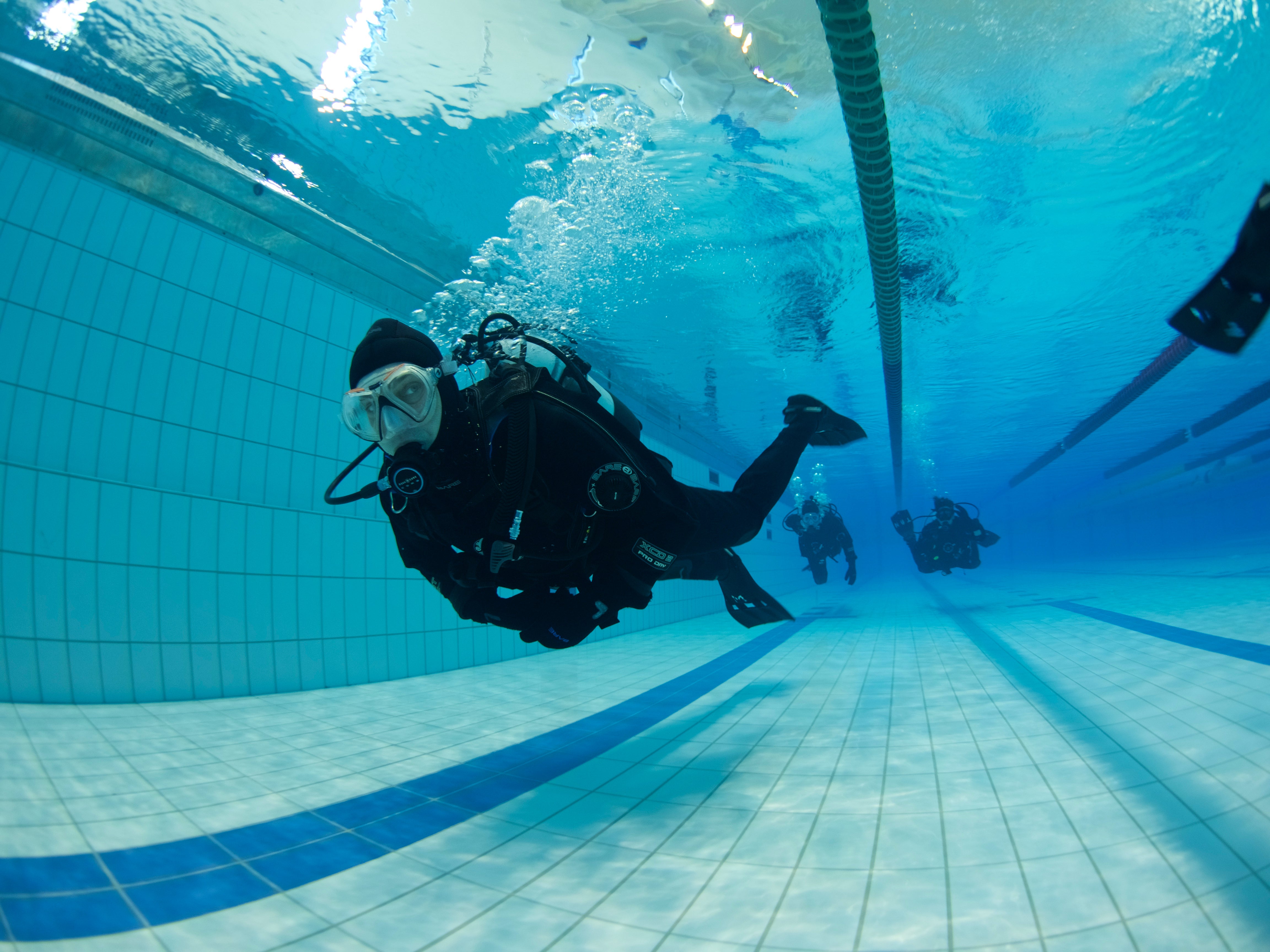 Divers training in a indoor pool during a private PADI Dry Suit Diver Course in Iceland.