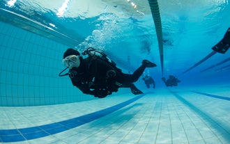 Divers training in a indoor pool during a private PADI Dry Suit Diver Course in Iceland.