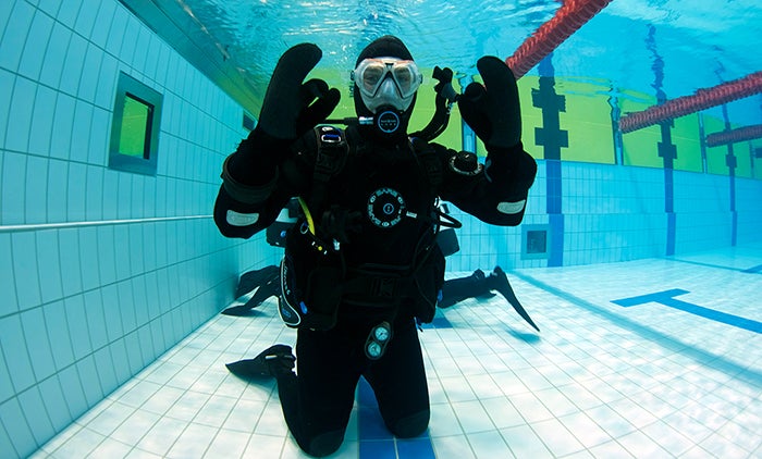 A scuba diver in Iceland under a pool posing for a photo.