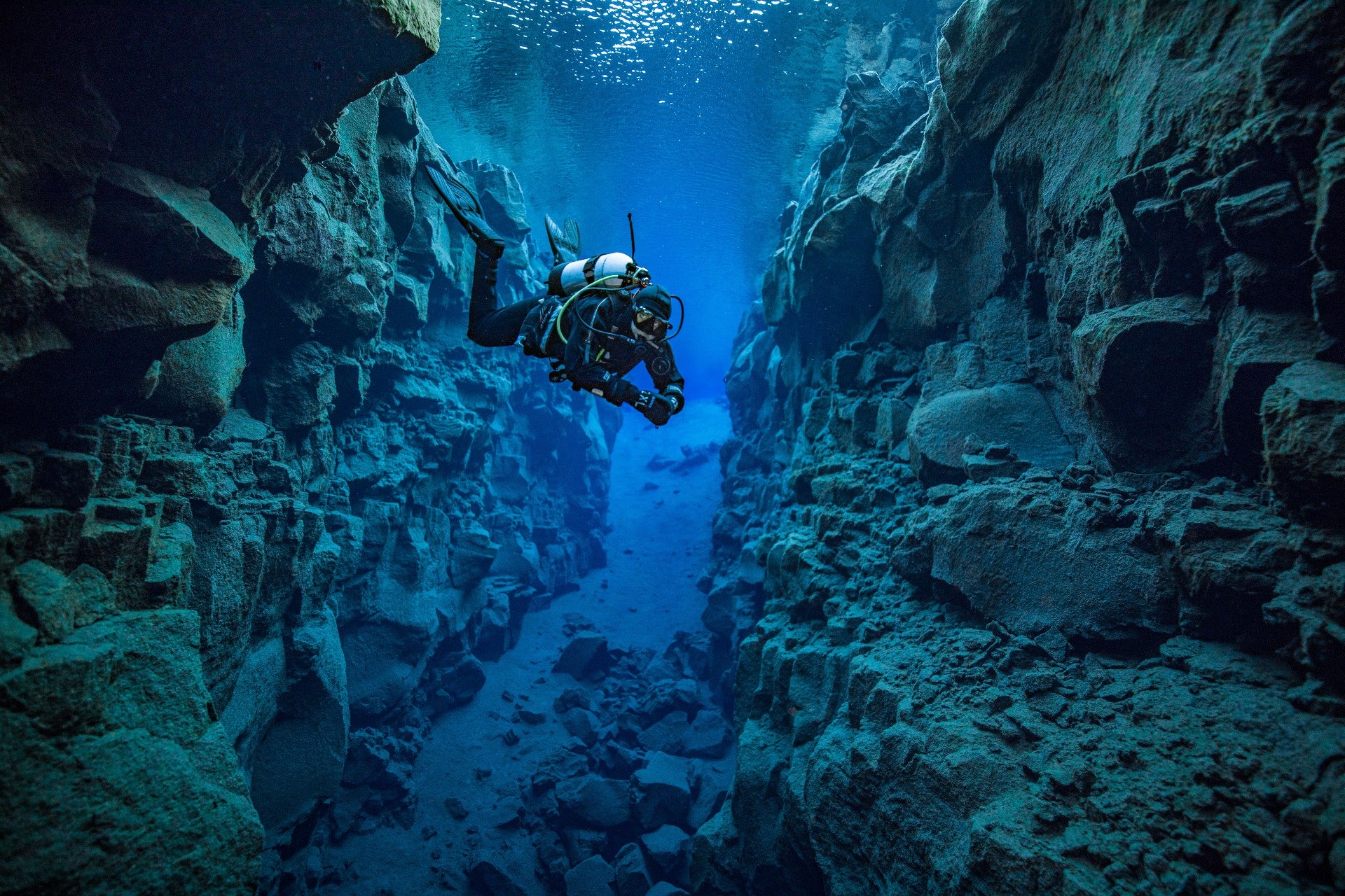 Scuba diver exploring Silfra Fissure’s vibrant underwater canyon, surrounded by volcanic rock formations.