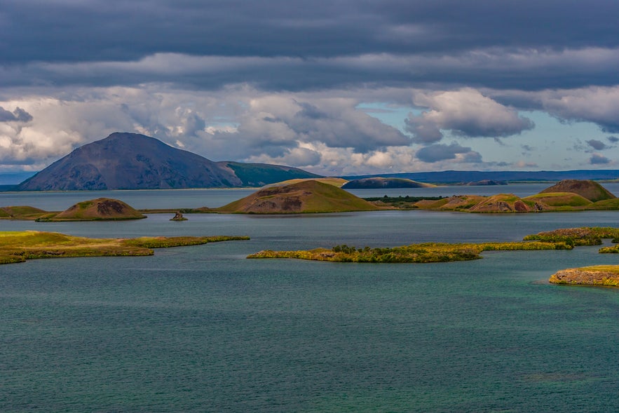 Volcanic landscape of Lake Myvatn in northern Iceland, featuring lava formations, grassy islets, and distant mountains.