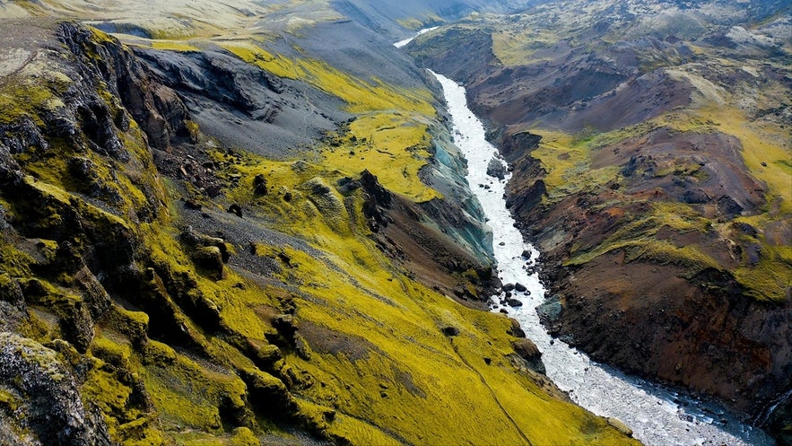 Aerial view of the Fossa River winding through a rugged, moss-covered canyon in a volcanic landscape.