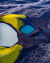 Overhead view from an Iceland helicopter tour in the highlands, featuring braided rivers and mountain lakes.