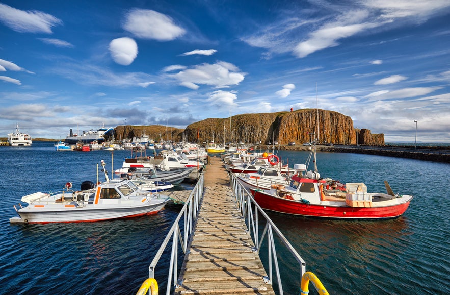 Stykkisholmskirkja Harbor with fishing boats at Stykkisholmur, Iceland, seen from Sugandisey Cliff with lighthouse.