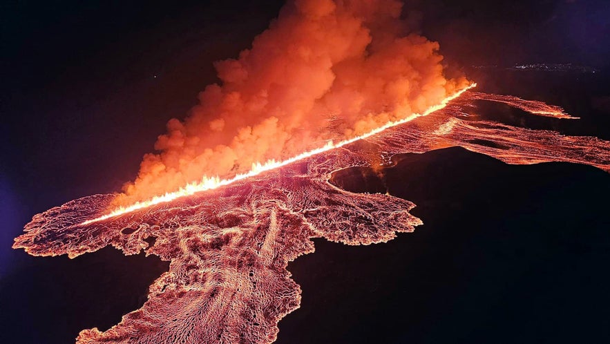 Aerial view of the 2024 Sundhnukagigar eruption with glowing lava and a long fissure spewing fire and smoke at night