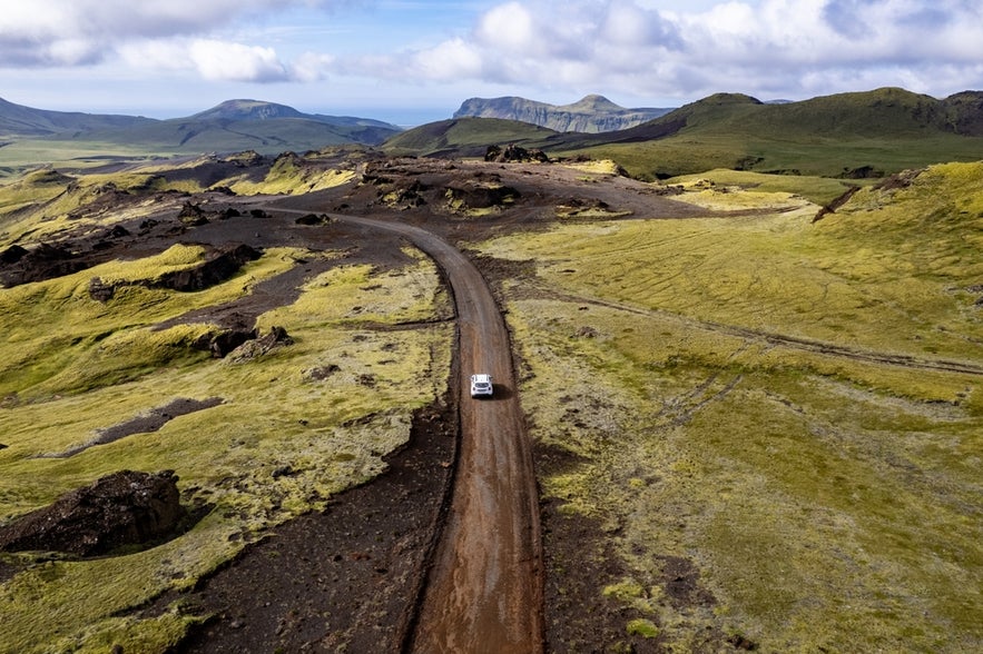 Aerial view of a 4x4 on a dirt road near Vik, a remote route often used to reach natural sites like Yoda Cave in South Iceland.