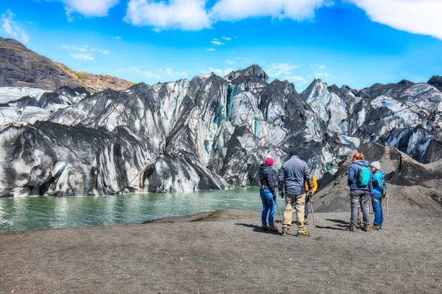 Hikers at the edge of Myrdalsjokull Glacier in South Iceland, viewing ice formations near popular sites like Yoda Cave and Vik.