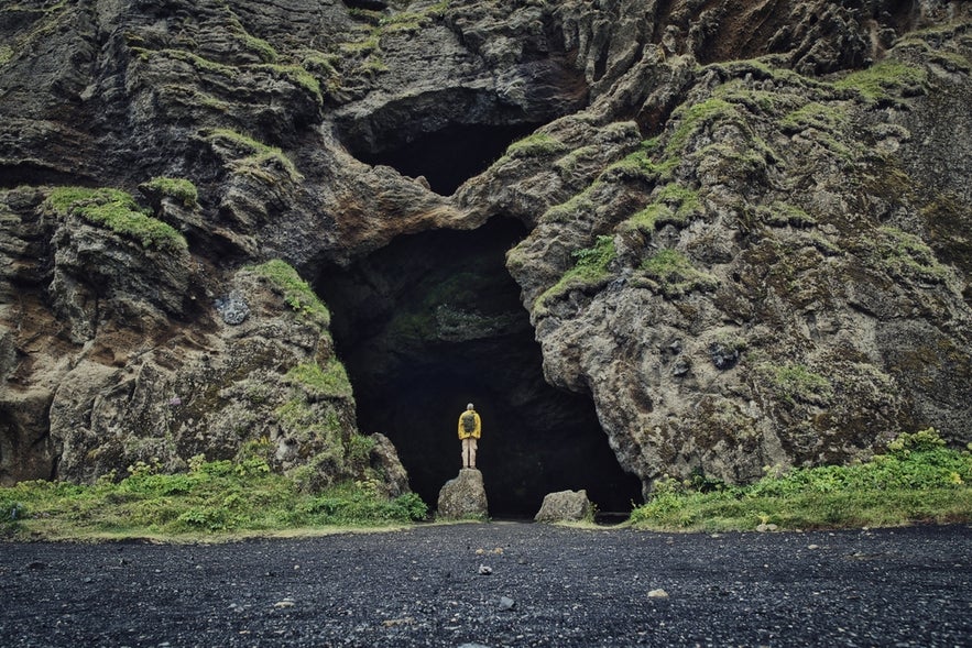 Traveler stands at the entrance of Yoda Cave in South Iceland, named for its opening that resembles Yoda from Star Wars.