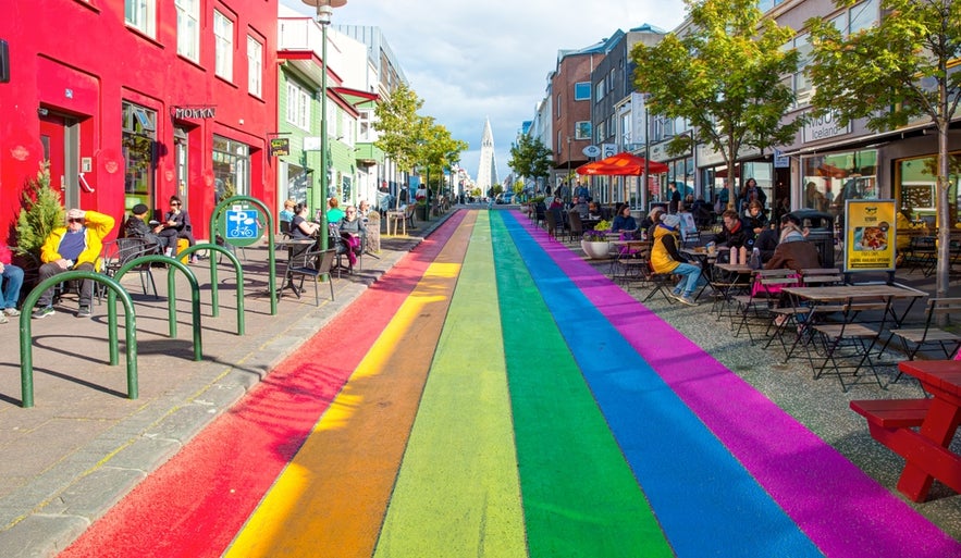 Colorful rainbow-painted Skolavordustigur street in Reykjavik, lined with shops, cafes, and views of Hallgrimskirkja.