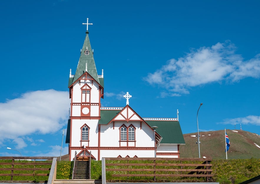 Husavik Church, a historic landmark near Dettifoss Waterfall in North Iceland, under a bright blue summer sky.