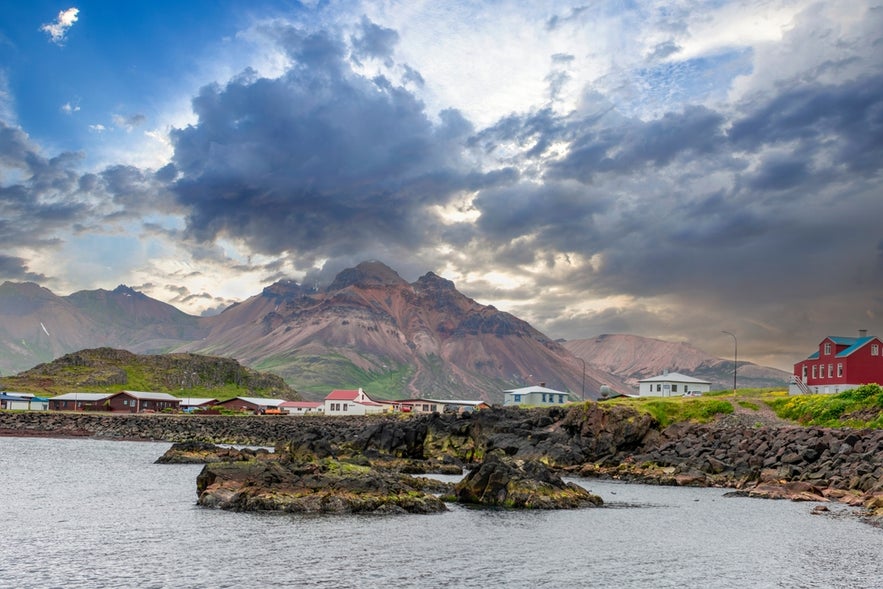 Colorful houses in Borgarfjordur Eystri, East Iceland, set against dramatic mountains and a cloudy sky by the sea.