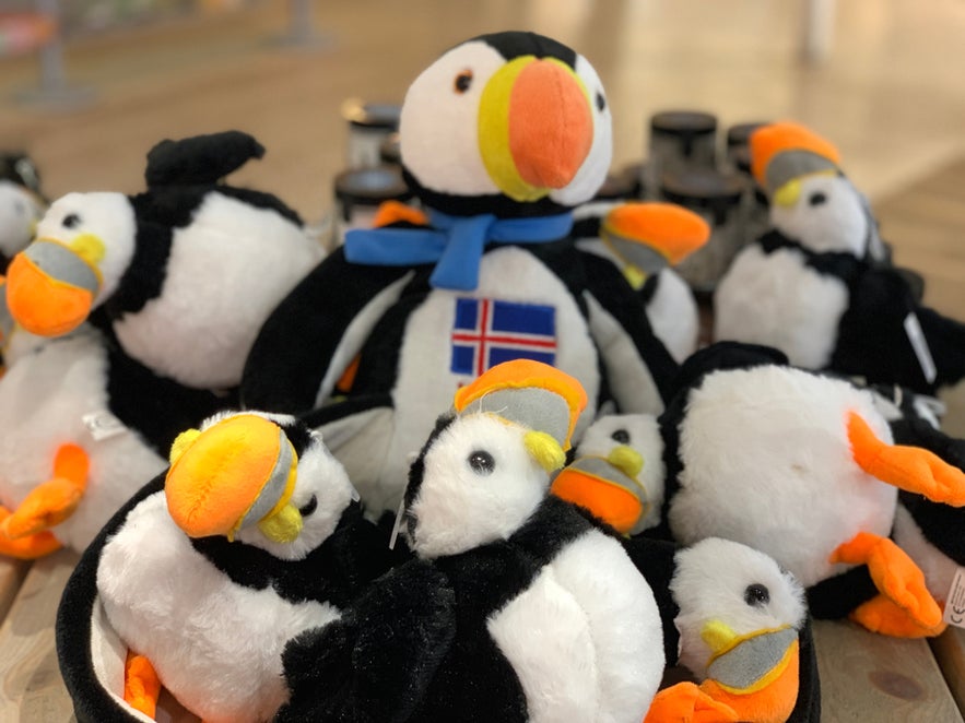 Display of plush puffin toys, including one with an Icelandic flag scarf, at a souvenir shop in Iceland.