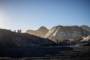 A group of people is seen walking around Katla glacier during golden hour.