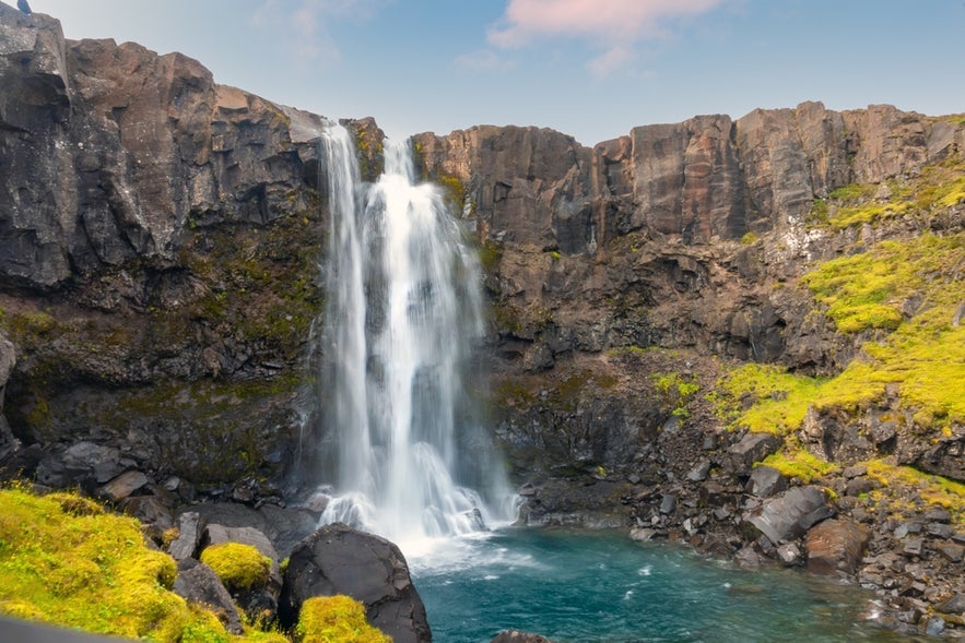 Gufufoss Waterfall near Seydisfjordur, Iceland cascading into a rocky pool surrounded by cliffs and summer greenery.