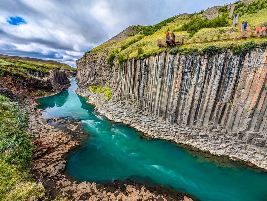 Studlagil Canyon near Seydisfjordur, Iceland with basalt columns, turquoise river, and people on a viewing platform.