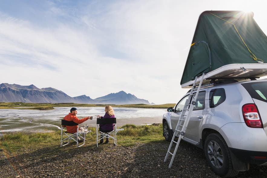 Camper van con tenda sul tetto parcheggiato in un paesaggio islandese aperto durante la stagione dei viaggi di agosto.