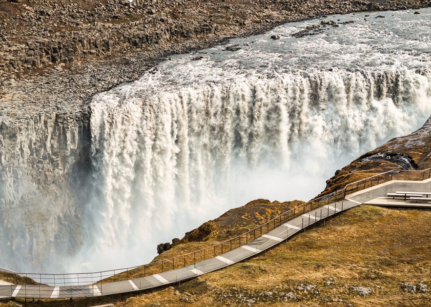 Dettifoss waterfall in Iceland, powerful water cascading over rocky cliffs with a walkway nearby.