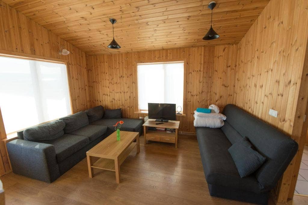 Two sofas, a wooden coffee table, and a TV on a wooden stand at Gladheimar cottages.