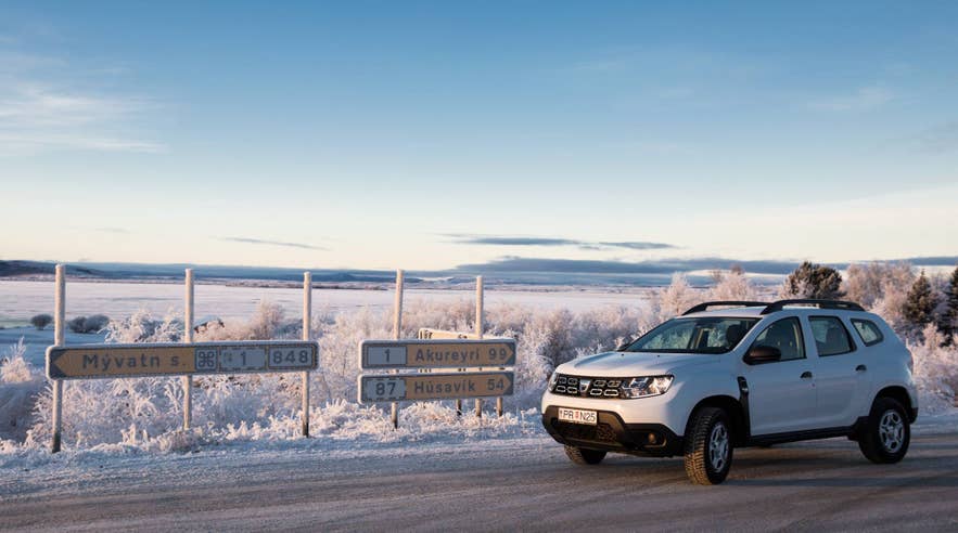 冰岛雪景中的SUV，展示前往阿克雷里、胡萨维克和米湖等城镇的出行方式和距离。